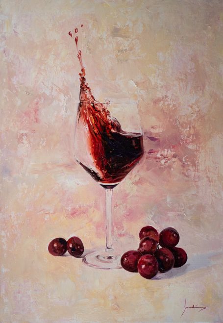 Copa de vino tinto con un salpicado, rodeada de uvas sobre un fondo suave.