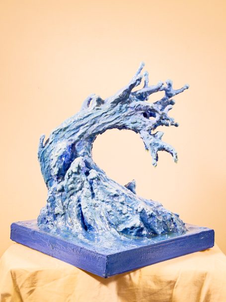 Escultura en forma de ola en tonos azules, con detalles de textura y movimiento.
