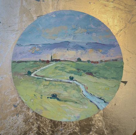 Paisaje circular con un río, campos verdes y montañas al fondo bajo un cielo azul.